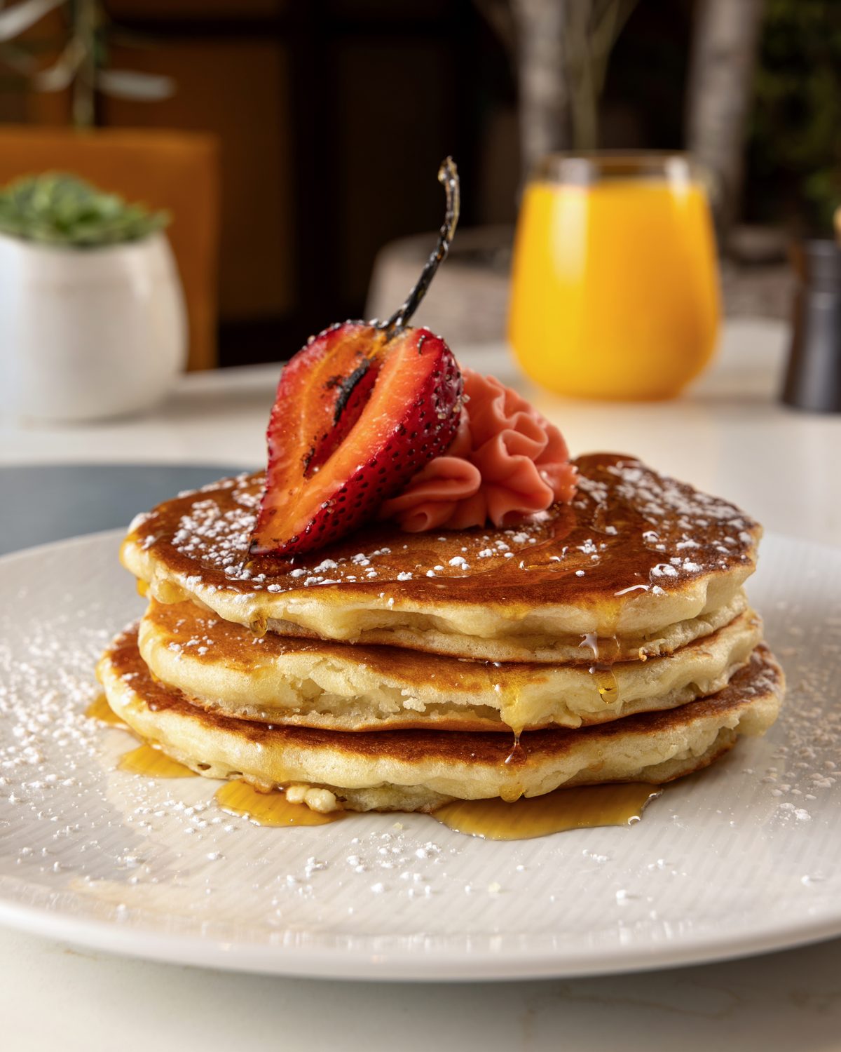 Stack of pancakes topped with a charred strawberry, strawberry butter, syrup and powdered sugar at Veranda, Four Seasons Las Vegas