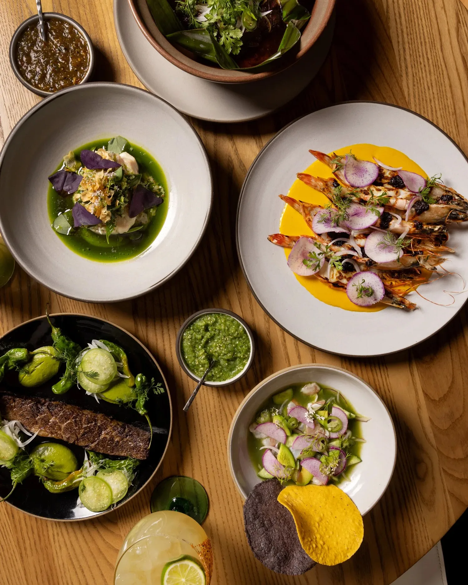Overhead table spread at Casa Playa: grilled prawns on yellow sauce, steak with shishito peppers, ceviche, salsas and a margarita