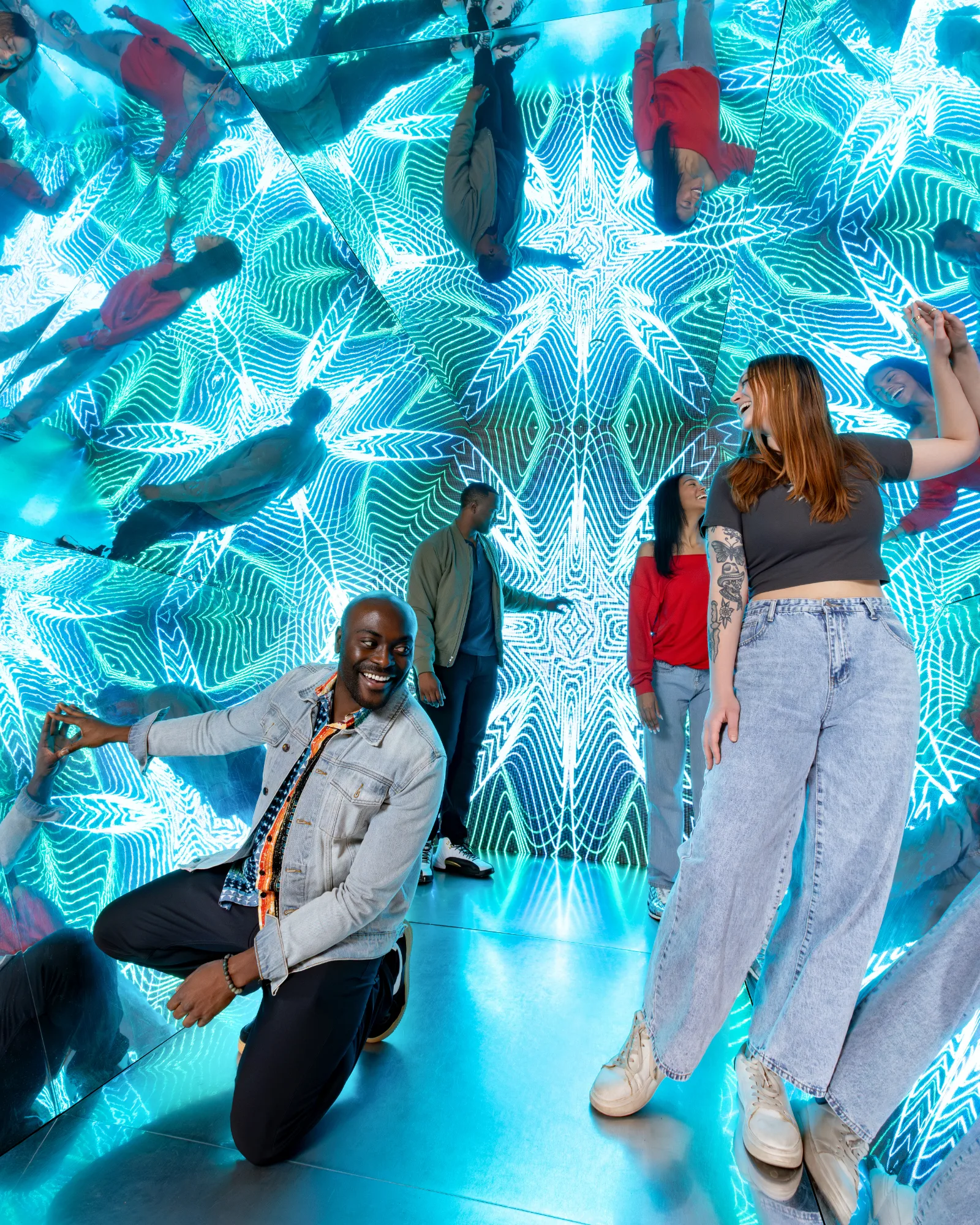 Visitors posing in a kaleidoscopic mirror room lit with blue neon patterns at Museum of Illusions